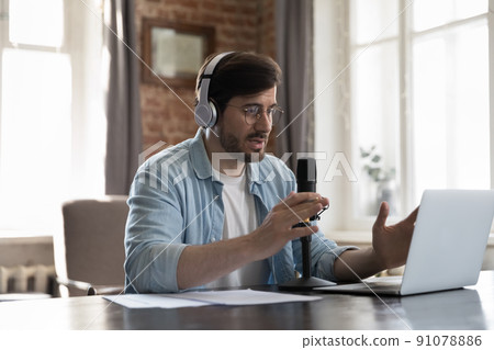 Man streamer wear headphones records podcast, makes speech into microphone 91078886