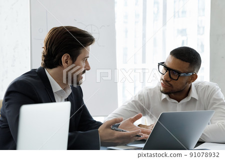 Multi racial businessmen talking during formal meeting in modern office 91078932