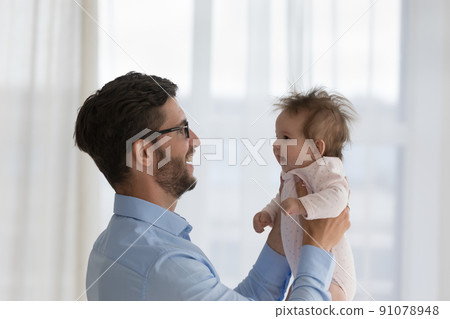 Young loving daddy holds lifts on hands his baby 91078948