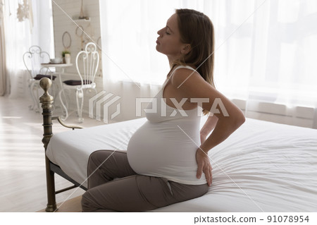Young pregnant woman feels discomfort in lower back Young pregnant woman feels discomfort in lower back 91078954
