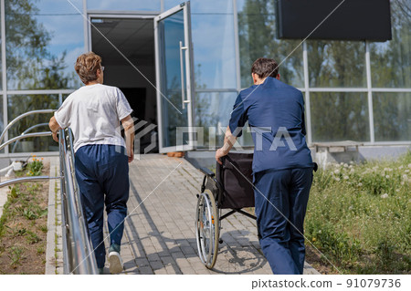 Patient and nurse turn around at clinic after a walk in courtyard  91079736