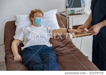 Nurse checking with fingertip pulse oximeter oxygen saturation of patient blood in hospital 91079738