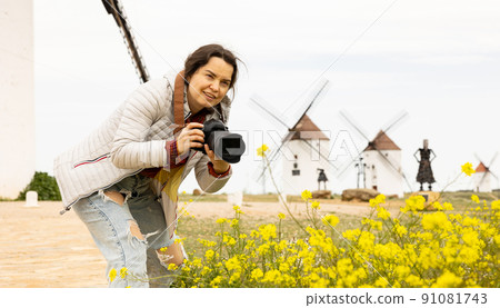 Woman tourist takes pictures of the windmills of Mota del cuervo. Spain 91081743