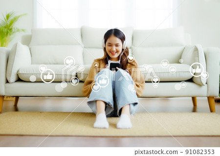 Young asian woman using mobile smartphone with icon social media and social network in living room Young asian woman using mobile smartphone with icon social media and social network in living room 91082353