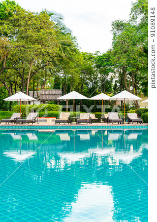 Umbrella and chair around swimming pool in hotel resort 91089148