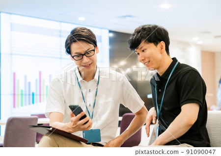 A casual business team talking while looking at the mobile screen A casual business team talking while looking at the mobile screen 91090047