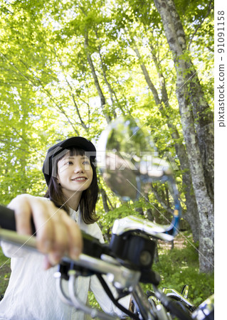 Bike girl image: A young woman straddling a motorcycle in the forest Bike girl image: A young woman straddling a motorcycle in the forest 91091158