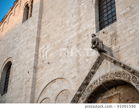 Bari, Puglia, Italy. August 2021. The imposing facade of the church of St. Nicholas, in Roman Catholic style. Detail of the main entrance door surmounted by a gargoyle Bari, Puglia, Italy. August 2021. The imposing facade of the church of St. Nicholas, in Roman Catholic style. Detail of the main entrance door surmounted by a gargoyle 91091598