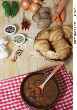 Beef Stew and Fresh Bread in Rustic Kitchen With Red and White Checkered Cloth 91092425