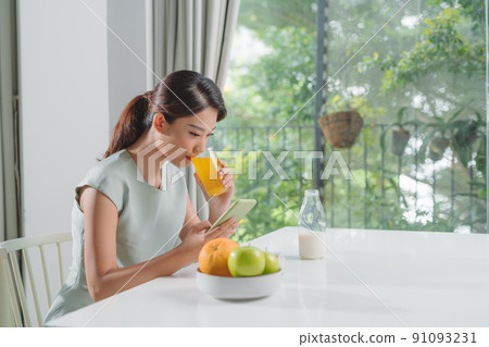 The girl has a healthy breakfast on stylish cozy home at the morning while checking her email on mobile. The girl has a healthy breakfast on stylish cozy home at the morning while checking her email on mobile. 91093231