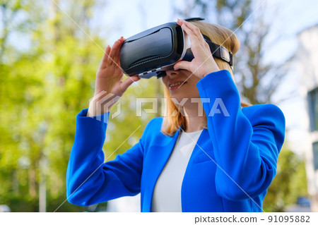 Woman with VR virtual reality goggles experiences a metaverse world. Augmented reality technology concept Woman with VR virtual reality goggles experiences a metaverse world. Augmented reality technology concept 91095882
