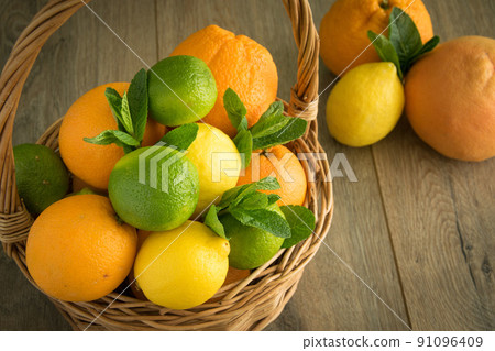 High angle view wicker handbasket full citrus fruits on wooden table High angle view wicker handbasket full citrus fruits on wooden table 91096409