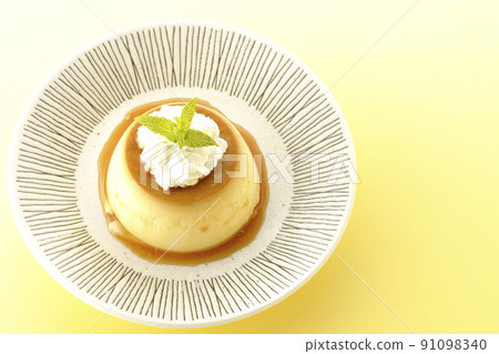 A bird's-eye view of the old-fashioned retro pudding with mint leaves and fresh cream served on a flat plate. 91098340