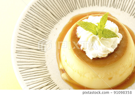 A bird's-eye view of the old-fashioned retro pudding with mint leaves and fresh cream served on a flat plate. 91098358