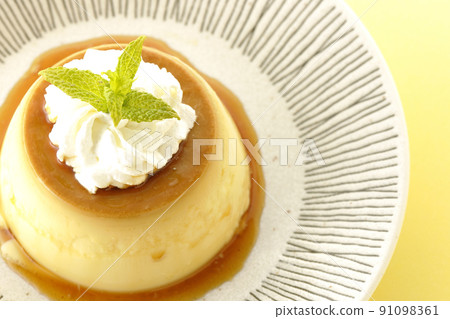 A bird's-eye view of the old-fashioned retro pudding with mint leaves and fresh cream served on a flat plate. 91098361