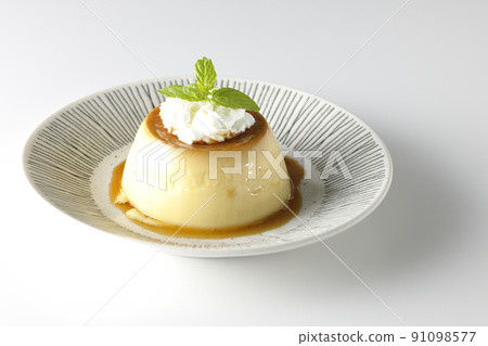 A white background of old-fashioned retro pudding with mint leaves and fresh cream served on a flat plate. 91098577