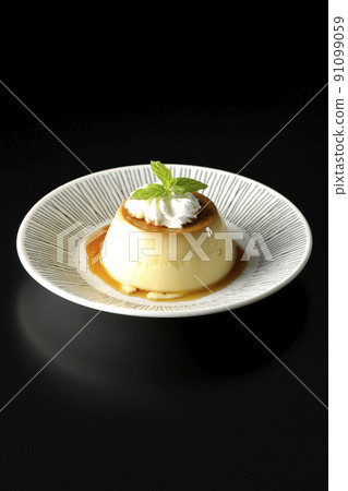 黑色背景的老式複古布丁配薄荷葉和新鮮奶油，放在平板上。 91099059