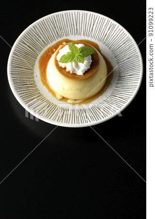 老式複古布丁的鳥瞰圖，上面有薄荷葉和新鮮奶油，放在黑色背景的平板上。 91099223