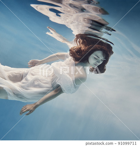 A girl in a dress with lace swims underwater as if in zero gravity 91099711