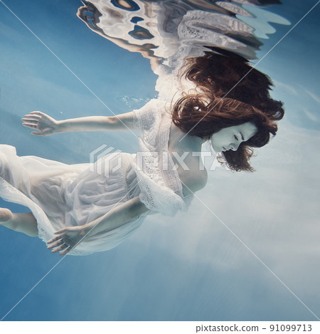 A girl in a dress with lace swims underwater as if in zero gravity 91099713