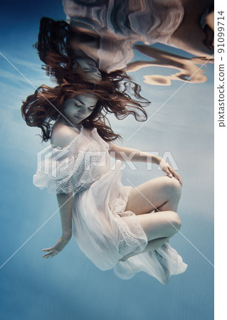 A girl in a dress with lace swims underwater as if in zero gravity 91099714