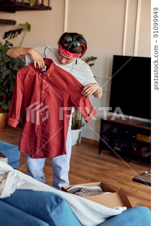 Asian guy reviewing his online purchases at home Asian guy reviewing his online purchases at home 91099949