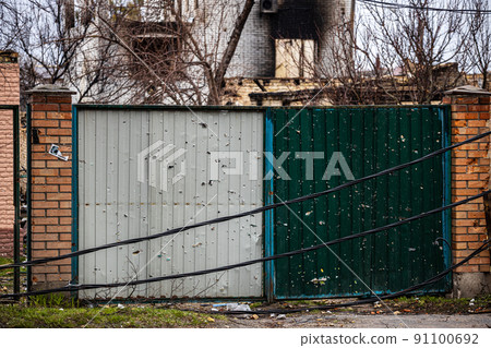 Irpin, Kyev region Ukraine - 09.04.2022: Gates fired upon by Russian soldiers, occupiers. The gates, the fence, the house were shot from a machine gun, a machine gun. 91100692