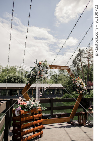 wooden wedding arch for the ceremony with flowers and decor near the water in the park 91100723