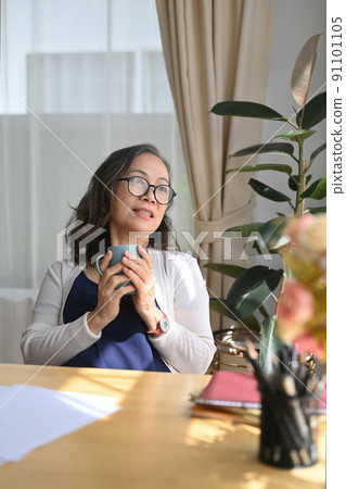 Happy middle aged woman holding cup of coffee, enjoy stress free peaceful mood wellbeing in comfortable home Happy middle aged woman holding cup of coffee, enjoy stress free peaceful mood wellbeing in comfortable home 91101105