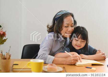 Loving mature grandma helping little grandchild doing homework. Multi generational, family and love concept 91101114