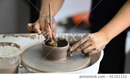 Cropped image of woman creating handmade ceramic bowl on the pottery wheel in workshop. Indoors lifestyle activity, handicraft, hobbies concept 91101152