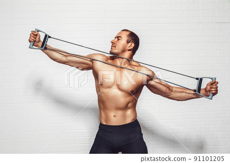 Handsome young sportsman exercising using expander while standing against white background 91101205