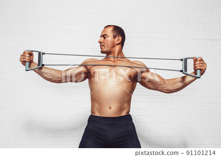 Handsome young sportsman exercising using expander while standing against white background 91101214