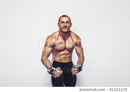 Handsome young sportsman exercising using expander while standing against white background 91101229