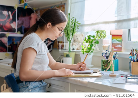 Teenage creative girl artist drawing with a pencil, sitting at the table at home Teenage creative girl artist drawing with a pencil, sitting at the table at home 91101504