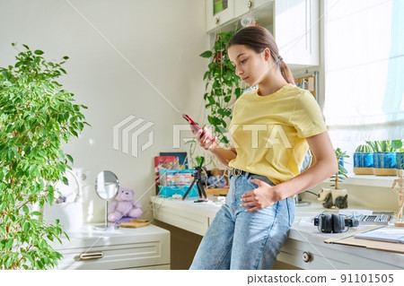 Teenage female using smartphone, resting at home in room, copy space Teenage female using smartphone, resting at home in room, copy space 91101505