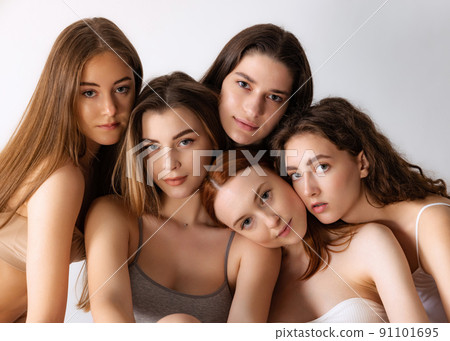 Portrait of beautiful young women with nude makeup posing, looking at camera isolated over grey studio background. Natural beauty Portrait of beautiful young women with nude makeup posing, looking at camera isolated over grey studio background. Natural beauty 91101695