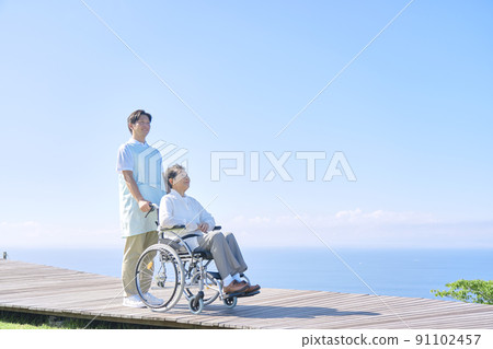 老年婦女和坐在輪椅上的護士一起去戶外 91102457