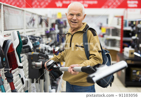 senor man pensioner buying Upright Vacuum Cleaner in showroom of electrical appliance store senor man pensioner buying Upright Vacuum Cleaner in showroom of electrical appliance store 91103056