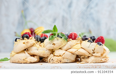 A baked cake made from whipped chicken protein and cream, decorated with fresh berries. Dessert Pavlova 91104354