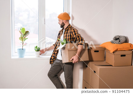 Mature man unpacking things from boxes while moving in new apartment. 91104475