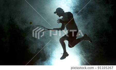 Jumping Player Hitting Tennis Ball with Atmosferic Smoke on Background Jumping Player Hitting Tennis Ball with Atmosferic Smoke on Background 91105267