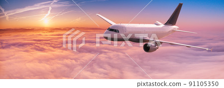 Commercial airplane jetliner flying above dramatic clouds in beautiful sunset light. Travel concept. 91105350