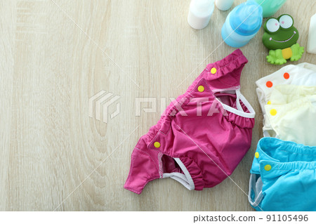 Concept of baby clothes with reusable diapers on wooden background 91105496