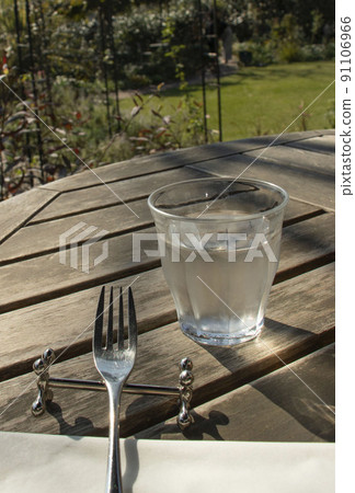 Glasses and forks placed on a wooden desk in a garden restaurant Glasses and forks placed on a wooden desk in a garden restaurant 91106966