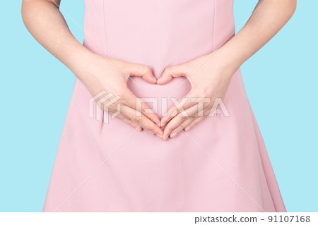 Close up of healthy woman hand made heart shape on her stomach. Concept of good digestive, healthy gut, probiotics, slim fit, gynecology and woman health care. Close up of healthy woman hand made heart shape on her stomach. Concept of good digestive, healthy gut, probiotics, slim fit, gynecology and woman health care. 91107168