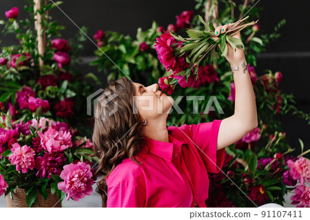 an attractive young woman in a pink blouse with peony flowers 91107411