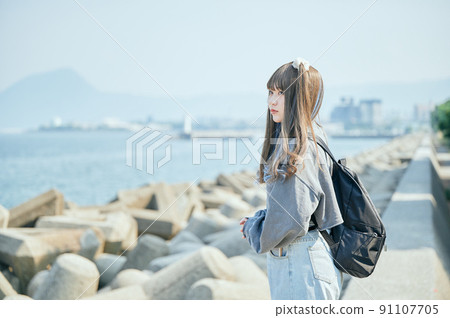 A young woman staring at the sea on a solo trip 91107705