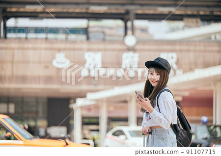 在別府站前用智能手機觀光的年輕女子 在別府站前用智能手機觀光的年輕女子 91107715