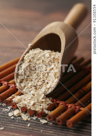 Close up of oats flakes on spoon on table Close up of oats flakes on spoon on table 91108554